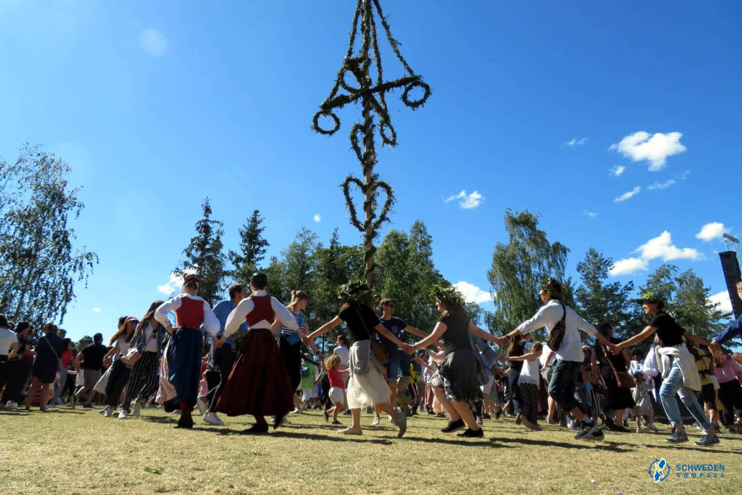 Schweden tanzen zu Midsommar um eine Maistange